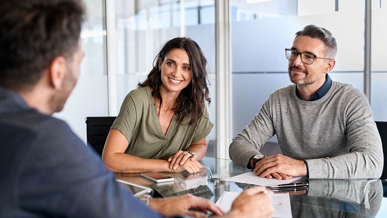 Happy middle aged couple meeting loan advisor to buy a new home