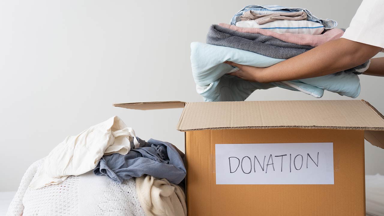 woman hands holding clothes putting in a donation box