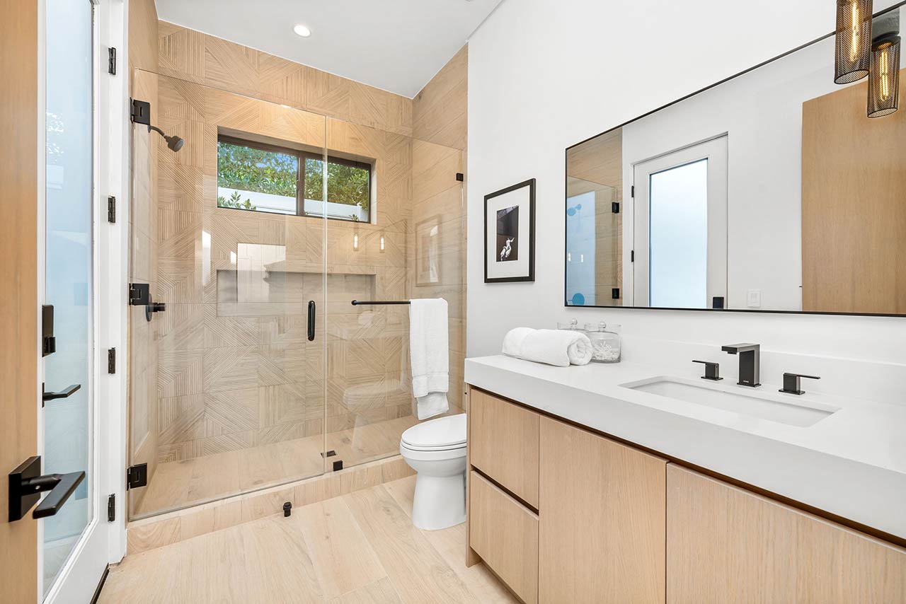 Modern bathroom with glass shower, wooden cabinets, and sleek fixtures in a bright, minimalist design